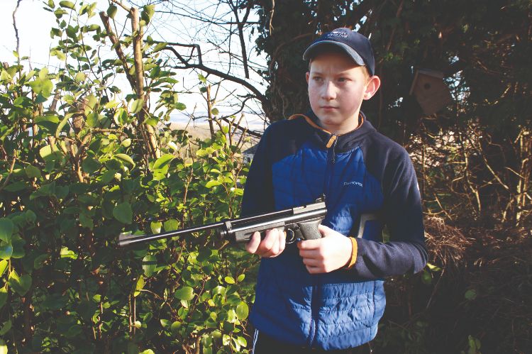 A young boy holding an air rifle