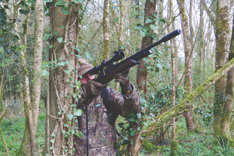 Mat Manning taking a standing shot with an air rifle in woodland